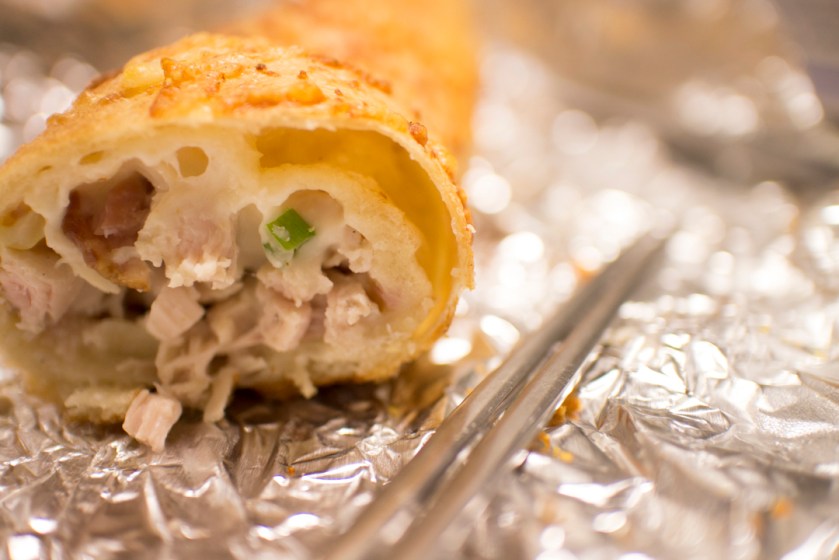 Lots of chicken chunks with cheese,ham, dressing, and green onions. There is more cheese baked on the outside.